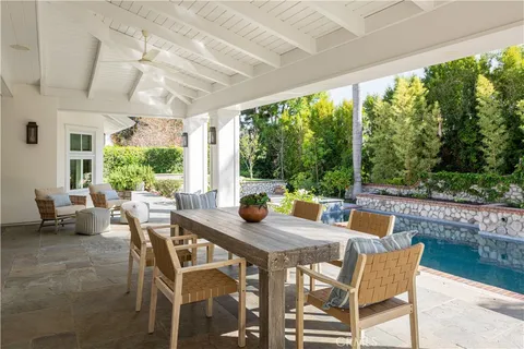 a view of a white house with large windows and a table and potted plants