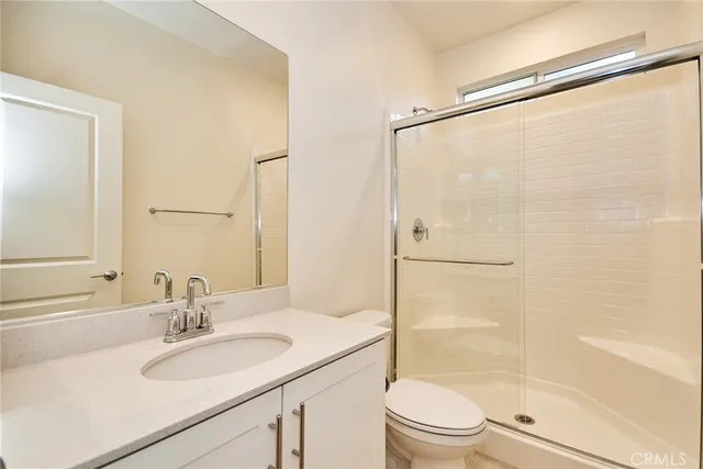 a bathroom with a sink a mirror toilet and shower