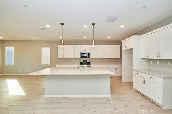 a view of a kitchen with kitchen island a sink stainless steel appliances and cabinets