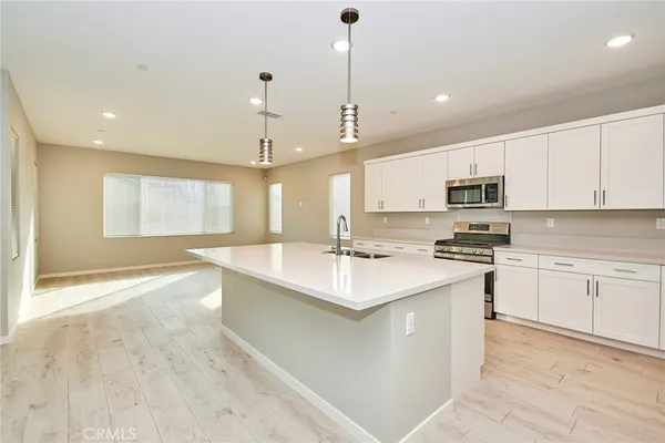 a kitchen with stainless steel appliances granite countertop a sink a stove a refrigerator and white cabinets with wooden floor