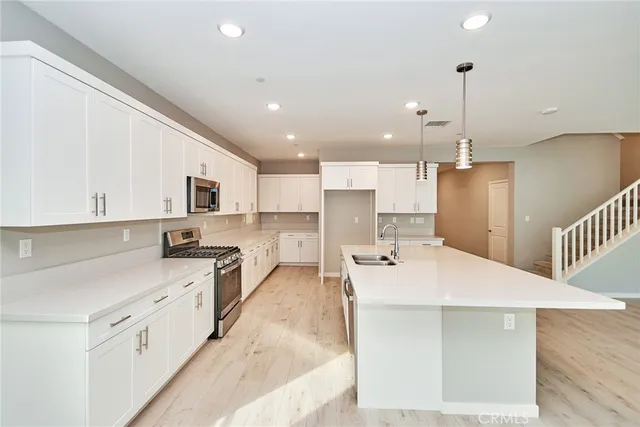 a large white kitchen with kitchen island a sink a center island stainless steel appliances and a center island