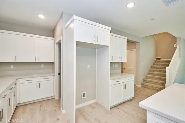 a view of a kitchen with white cabinets and wooden floor