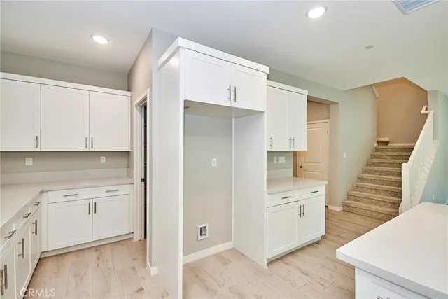 a view of a kitchen with white cabinets and wooden floor