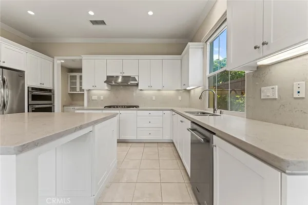 a large kitchen with granite countertop a sink and white cabinets
