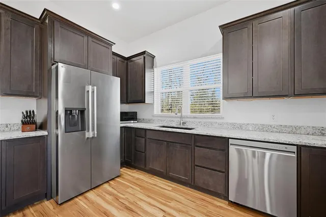 a large kitchen with stainless steel appliances kitchen island granite countertop a refrigerator a stove a sink dishwasher and a dining table with wooden floor