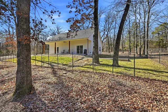 a view of a house with a yard and a large tree