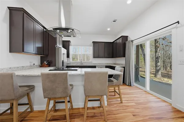 a kitchen with granite countertop a table chairs stove and microwave