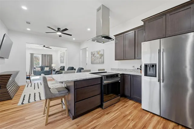 a kitchen with stainless steel appliances granite countertop a table chairs refrigerator and sink