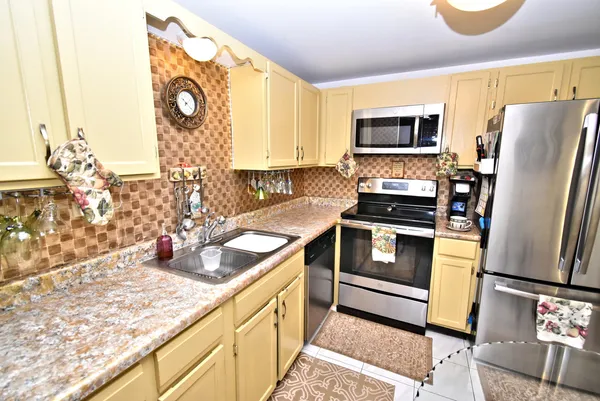 a kitchen with stainless steel appliances granite countertop a refrigerator a stove and a sink with wooden floor
