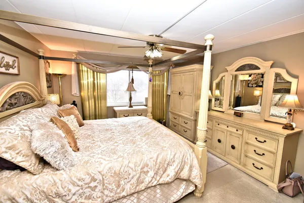 a bedroom with a bed a dresser and chandelier