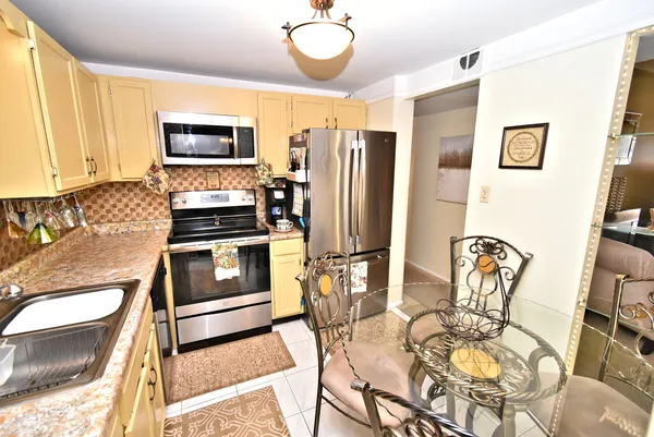 a kitchen with stainless steel appliances granite countertop a stove top oven a sink a dining table and chairs