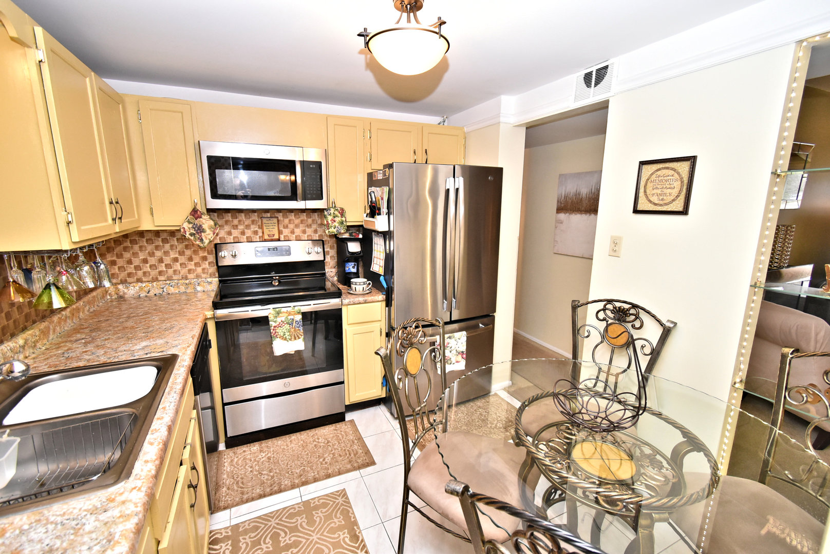 18855 Burnham Avenue, Unit 234 Lansing, IL 60438 - Photo 9 of 25 a kitchen with stainless steel appliances granite countertop a stove top oven a sink a dining table and chairs