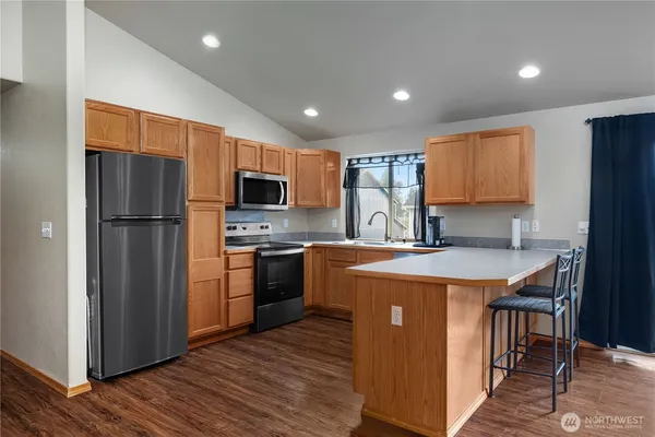 a kitchen with stainless steel appliances granite countertop a refrigerator a stove top oven a sink and dishwasher