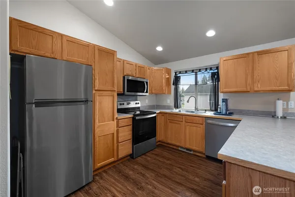 a kitchen with granite countertop a refrigerator stove top oven and sink