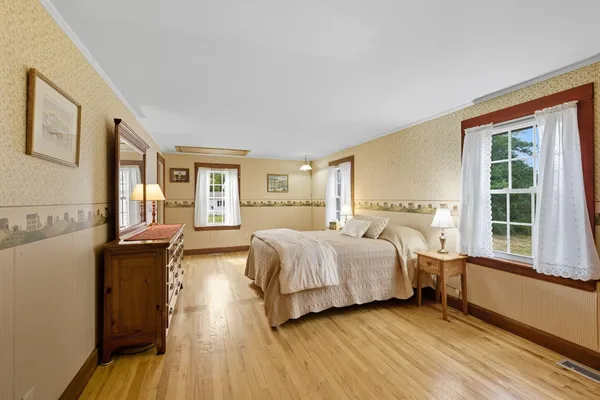 a spacious bedroom with a bed and wooden floor