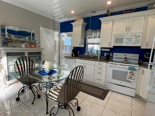 a kitchen with stainless steel appliances kitchen island granite countertop a table chairs and a refrigerator