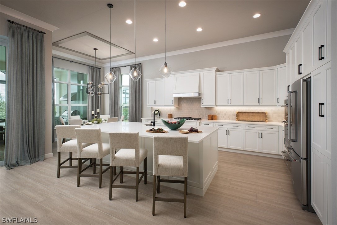 6181 Megans Bay Drive Naples, FL 34113 - Photo 3 of 32 a kitchen with a dining table chairs refrigerator and cabinets