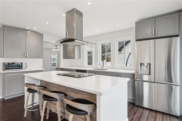 a kitchen with stainless steel appliances a refrigerator a stove a sink and white cabinets with wooden floor