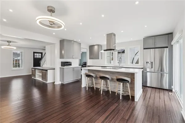 a kitchen with stainless steel appliances granite countertop a refrigerator a stove microwave and island with wooden floor