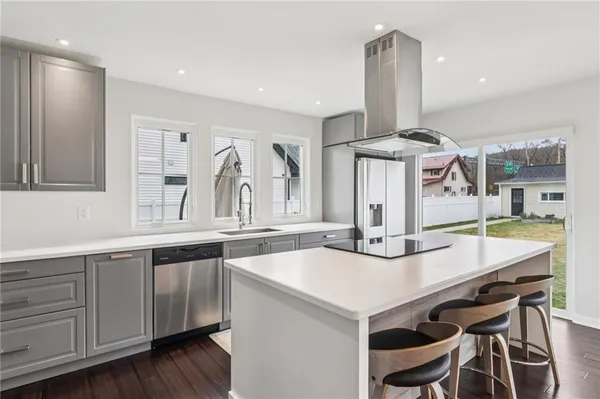 a kitchen with stainless steel appliances kitchen island a table chairs in it and wooden floors