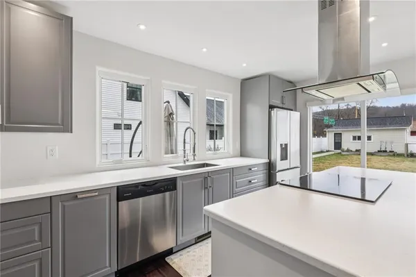 a large white kitchen with a sink and dishwasher a refrigerator with wooden cabinets