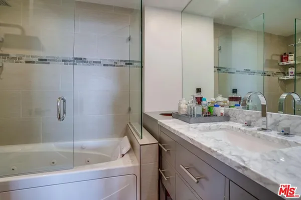 a bathroom with a granite countertop sink a mirror and bathtub