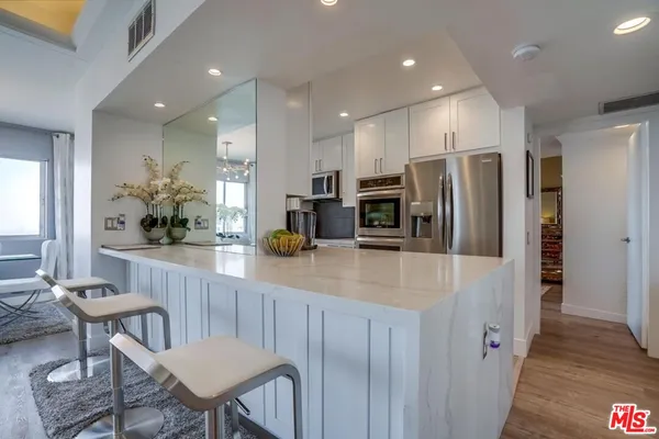 a kitchen with stainless steel appliances a refrigerator a stove a sink dishwasher with a dining table and chairs