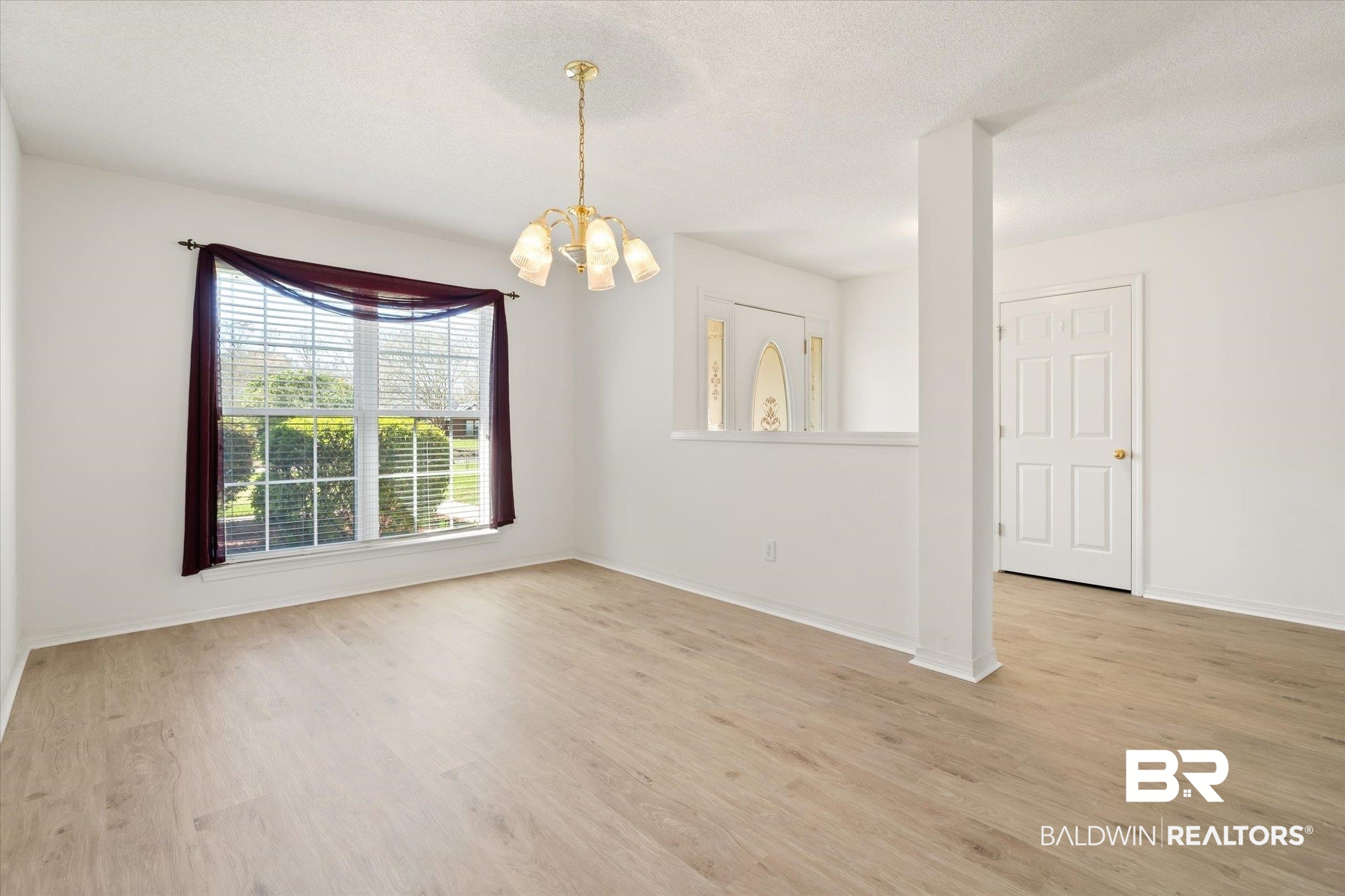 12520 Hunters Chase Foley, AL 36535 - Photo 15 of 32 Empty room featuring a notable chandelier, baseboards, light wood-type flooring, and a textured ceiling