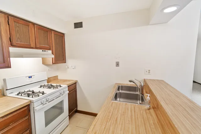 a kitchen with a stove wooden floor and cabinets