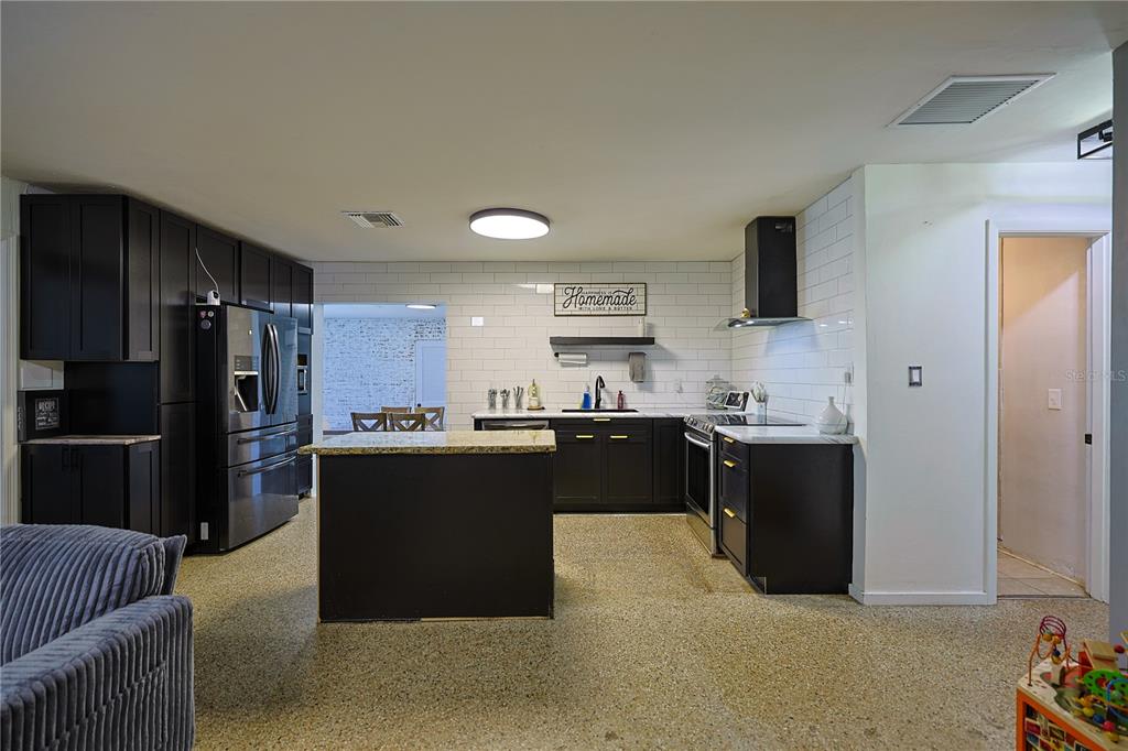 613 Scenic Street Leesburg, FL 34748 - Photo 8 of 38 a kitchen with stainless steel appliances kitchen island granite countertop a refrigerator and a sink