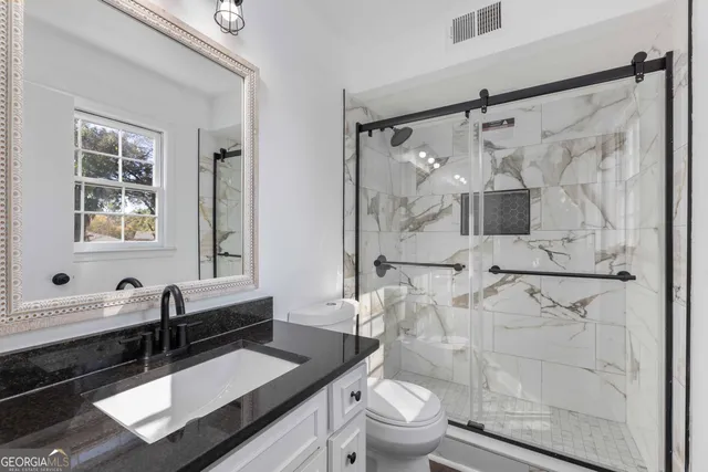 a bathroom with a sink a toilet and shower