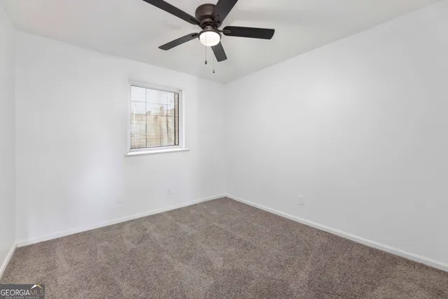 an empty room with a window and a fan