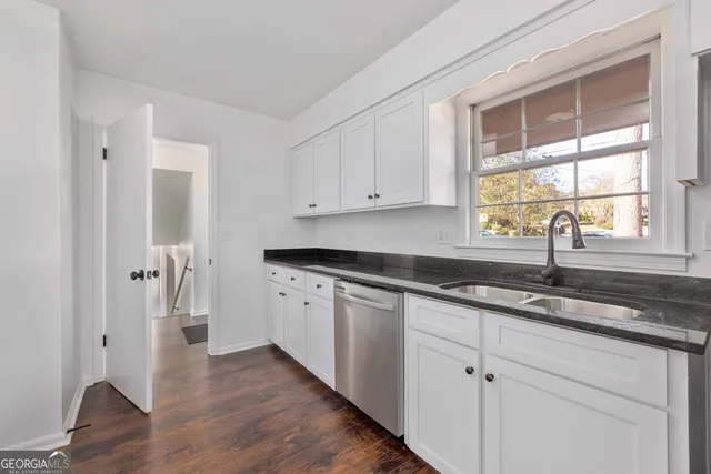 a kitchen with granite countertop white cabinets and a window