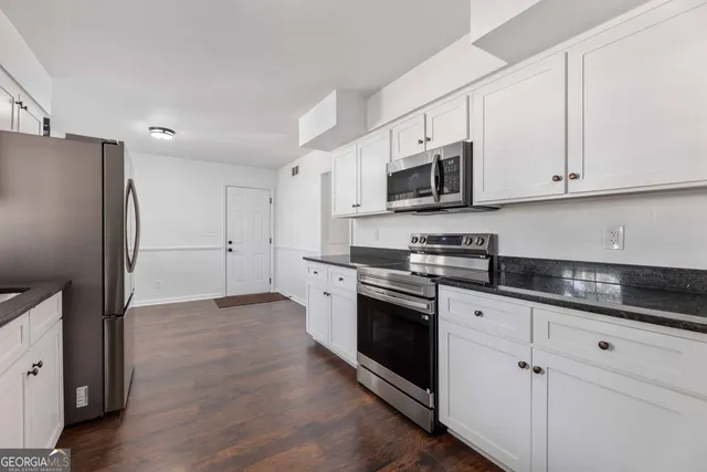 a kitchen with granite countertop white cabinets and stainless steel appliances