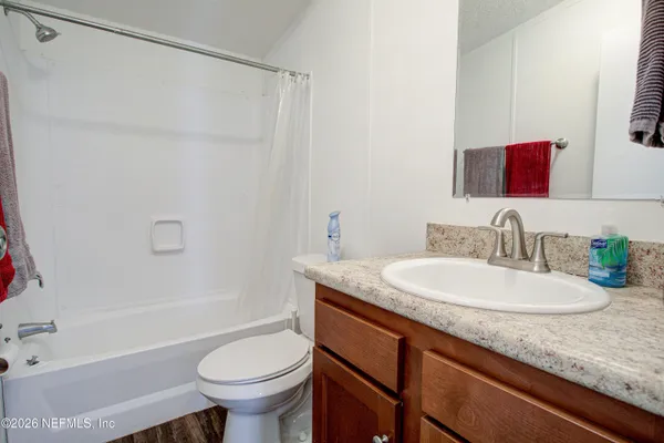 a bathroom with a granite countertop sink mirror vanity and toilet