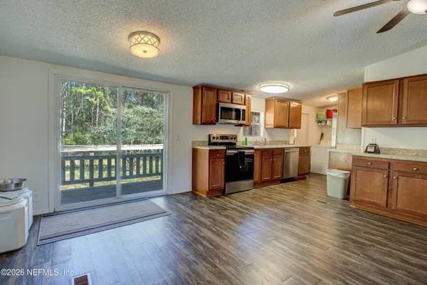 a open kitchen with stainless steel appliances granite countertop a stove top oven a sink dishwasher a dining table and chairs with wooden floor