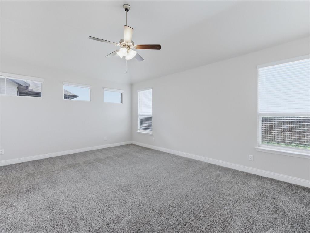 1121 Knightsbridge Road Argyle, TX 76226 - Photo 28 of 39 Spacious primary bedroom room featuring plush gray carpeting, white painted walls, and a ceiling fan with integrated lighting