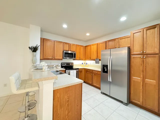 a kitchen with stainless steel appliances granite countertop a refrigerator a stove top oven a sink dishwasher and white cabinets with wooden floor