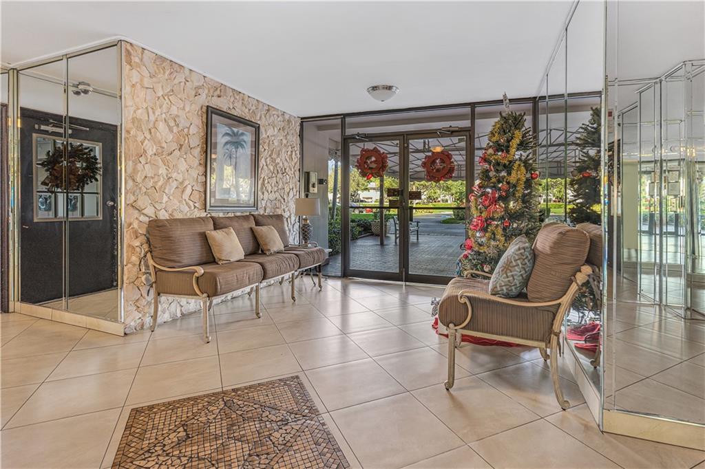 3100 North Palm Aire Drive, Unit 406 Pompano Beach, FL 33069 - Photo 14 of 16 a living room with furniture a chandelier and glass door