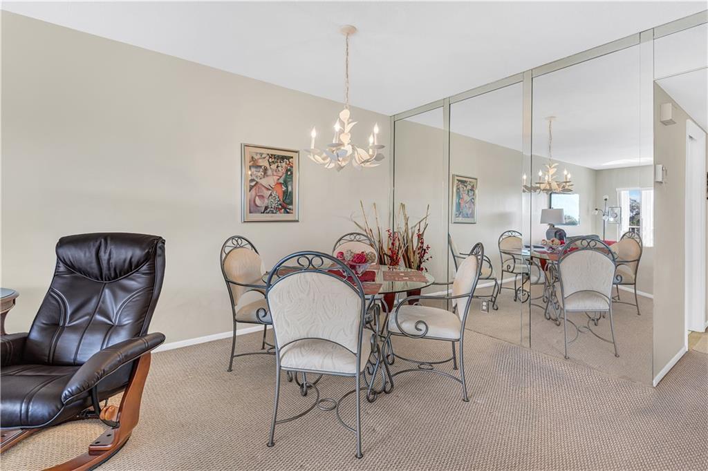 3100 North Palm Aire Drive, Unit 406 Pompano Beach, FL 33069 - Photo 7 of 16 a view of a dining room with furniture and chandelier