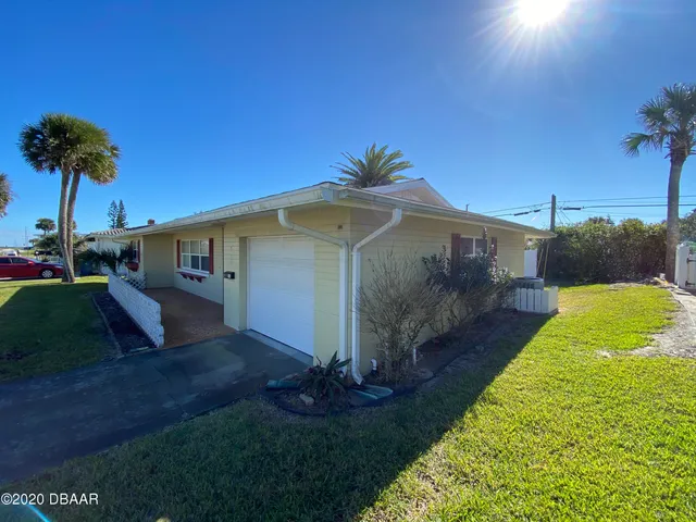 a front view of a house with a yard and palm trees