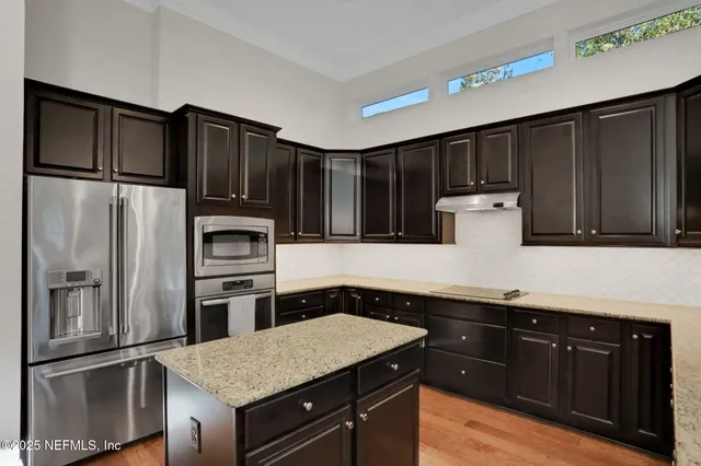 a kitchen with kitchen island granite countertop a sink a stove a refrigerator and cabinets