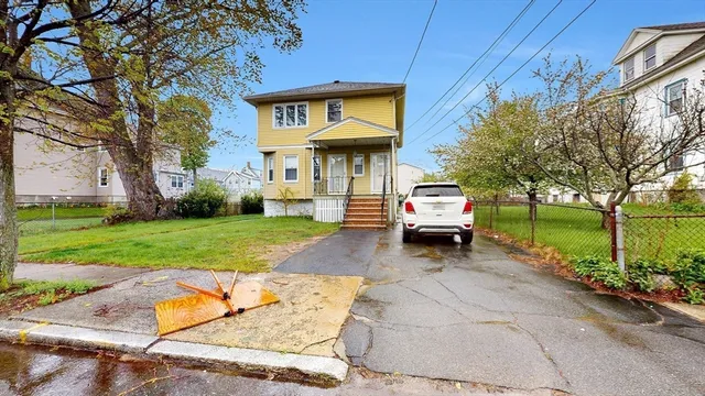 a car parked in front of a brick house with a large tree