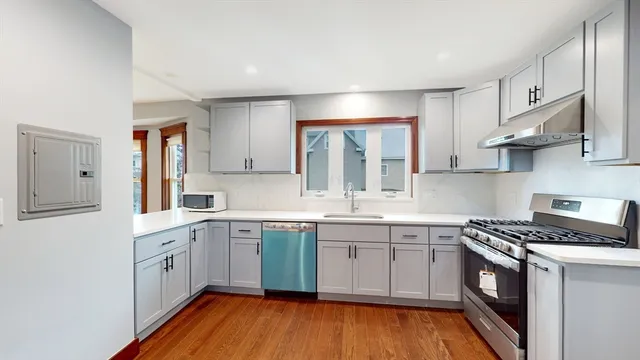a kitchen with stainless steel appliances white cabinets and wooden floors