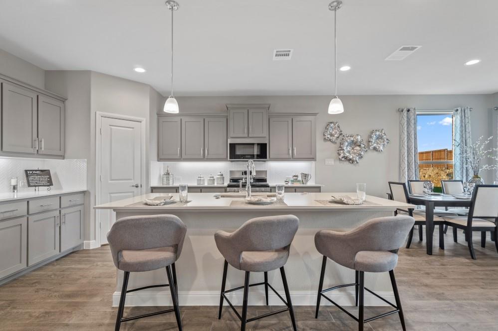105 Ringtail Drive Rhome, TX 76078 - Photo 1 of 40 a kitchen with sink a dining table and chairs with wooden floor