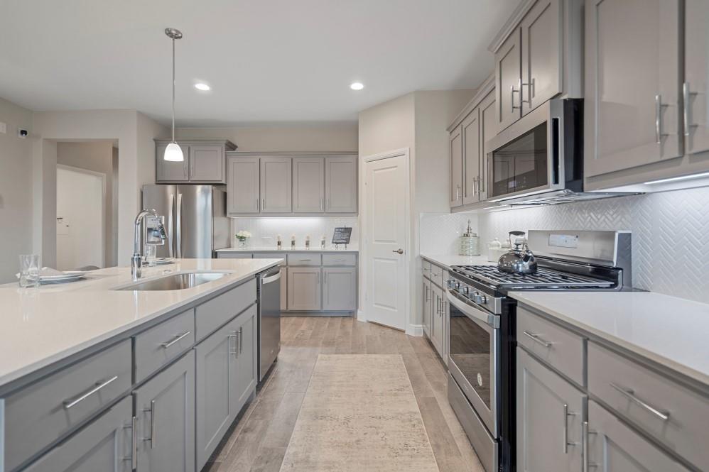 105 Ringtail Drive Rhome, TX 76078 - Photo 3 of 40 a kitchen with stainless steel appliances granite countertop a sink and dishwasher a stove top oven with wooden floor