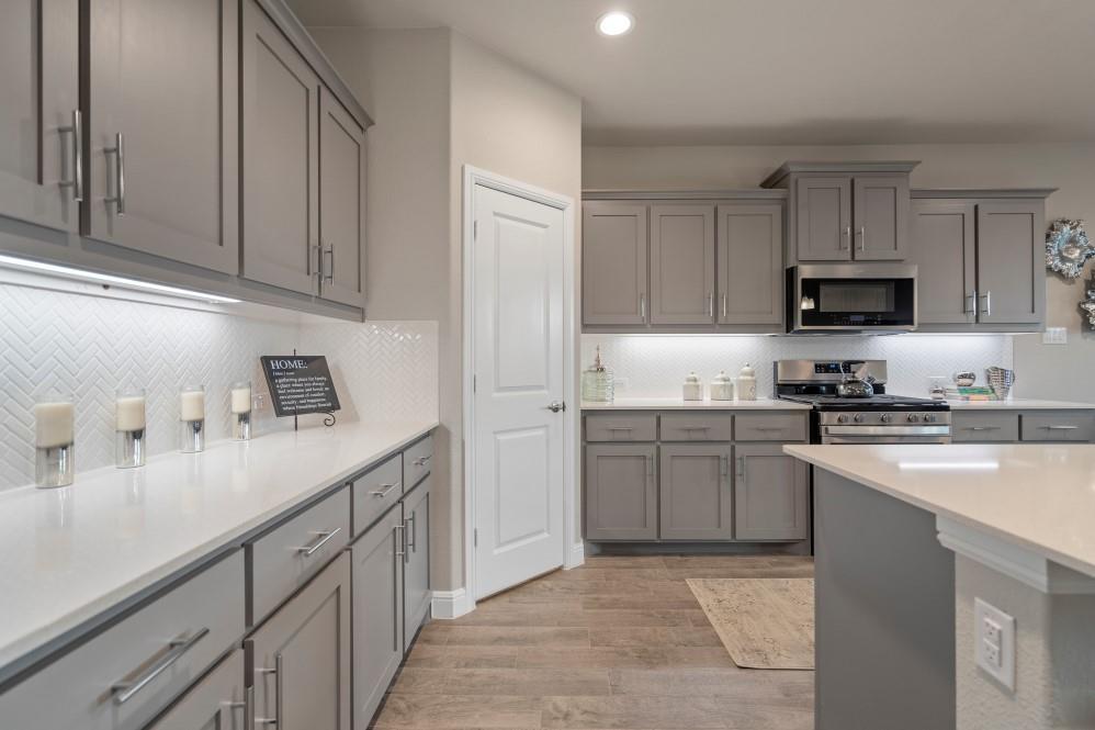 105 Ringtail Drive Rhome, TX 76078 - Photo 7 of 40 a kitchen with kitchen island granite countertop a sink dishwasher stove and white cabinets with wooden floor
