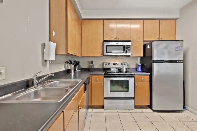 a kitchen with stainless steel appliances granite countertop a refrigerator a stove and a sink with dishwasher