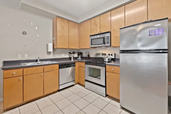 a kitchen with granite countertop stainless steel appliances a refrigerator sink and cabinets