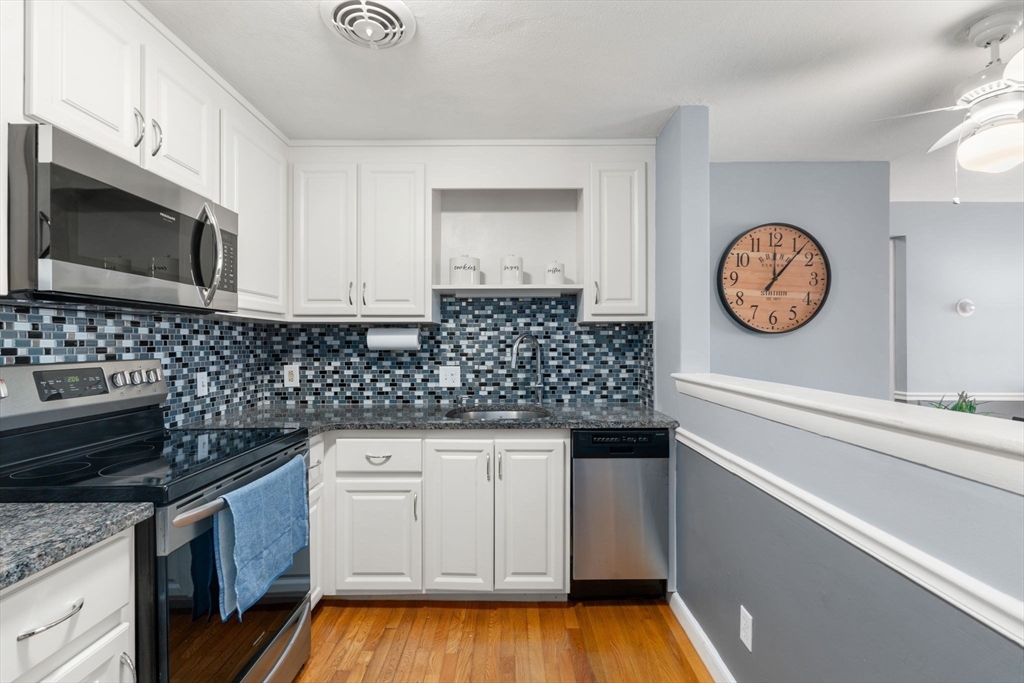 32 Whitman Road, Unit 14 Waltham, MA 02453 - Photo 7 of 20 a kitchen with granite countertop a stove a microwave a sink and cabinets